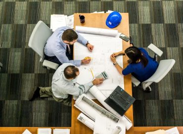 bovenaanzicht van drie mensen aan tafel met een groot kladpapier